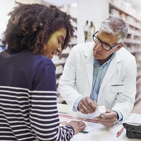 Pharmacist giving a customer prescription meds over the counter